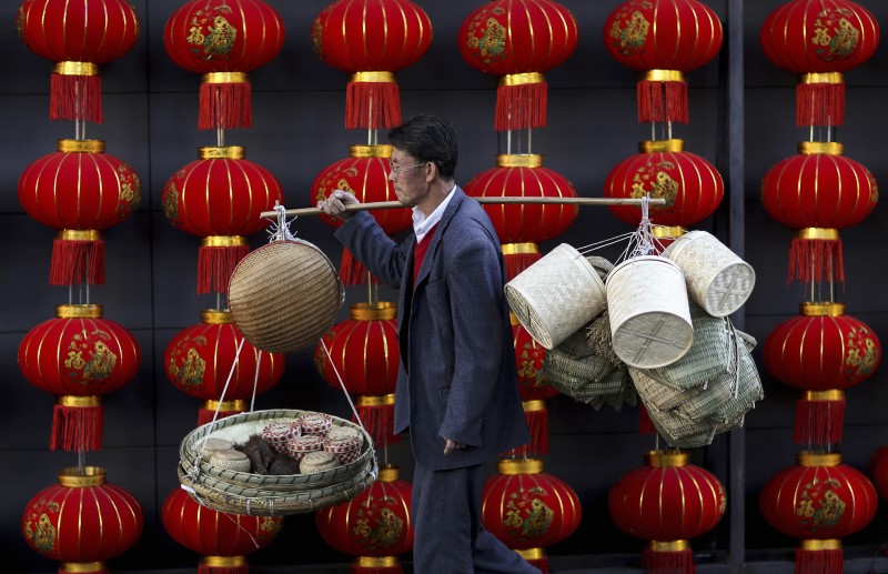 © Reuters. A basket vendor walks past red lanterns serving as decorations to celebrate the new year outside a shopping mall in Kunming
