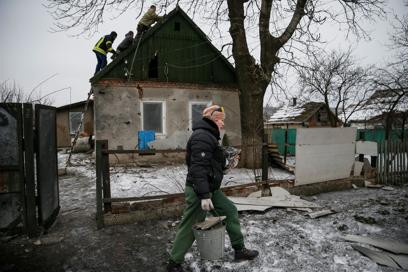 © Reuters. A local resident is seen as Emergencies Ministry members repair her home which was damaged during fighting between the Ukrainian army and pro-Russian separatists in the government-held industrial town of Avdiyivka