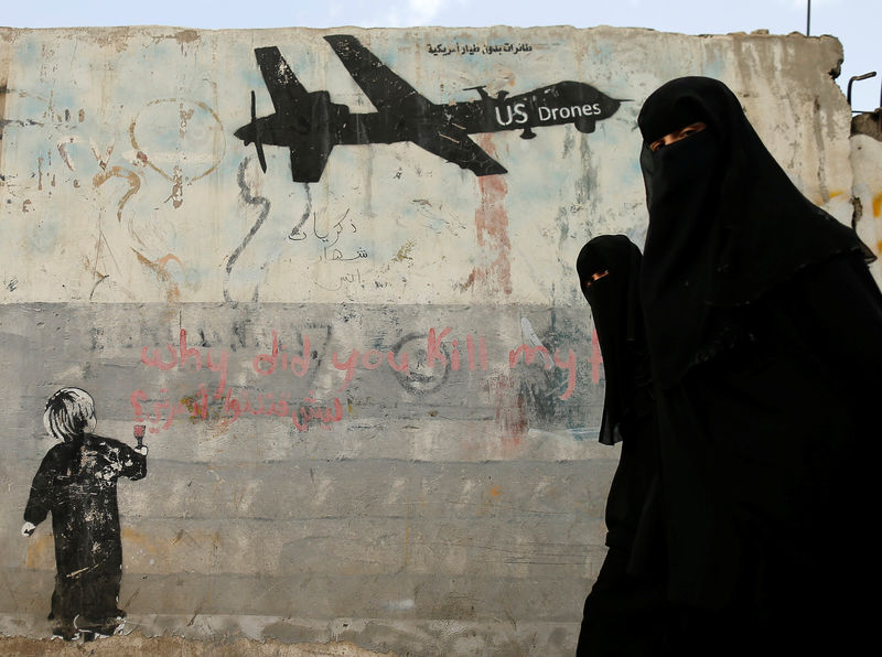 © Reuters. Women walk past a graffiti, denouncing strikes by U.S. drones in Yemen, painted on a wall in Sanaa, Yemen