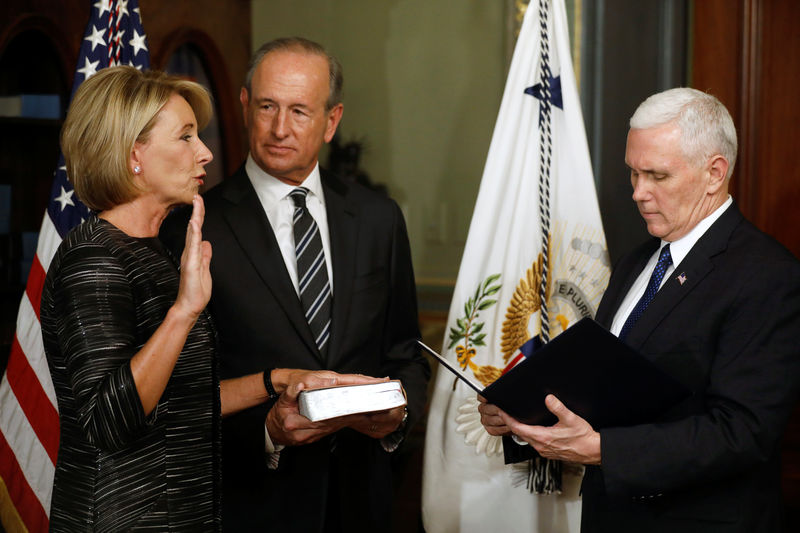 © Reuters. U.S. Vice President Mike Pence swears in Education Secretary Betsy DeVos, joined by her husband Dick DeVos, at the Eisenhower Executive Office Building at the White House