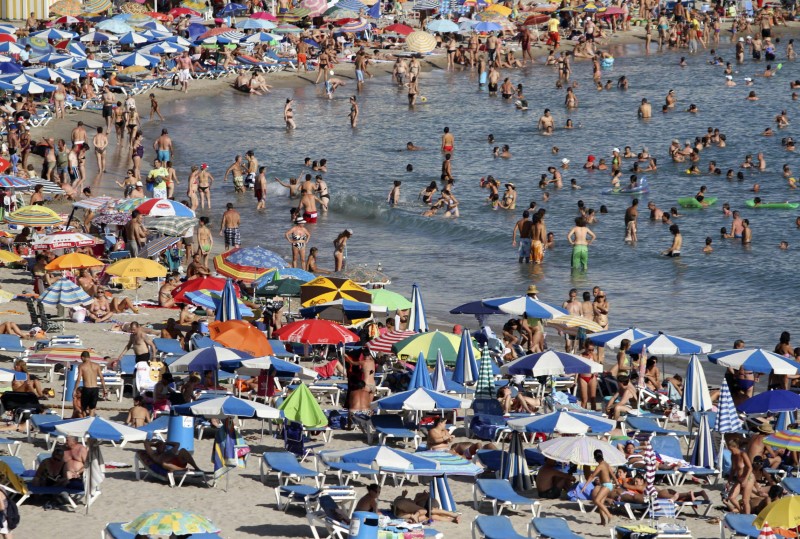 © Reuters. People sunbathe and swim on a beach in Benidorm