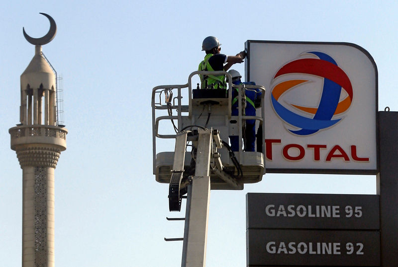 © Reuters. FILE PHOTO: Workers fix a sign for oil giant Total at a petrol station in Cairo