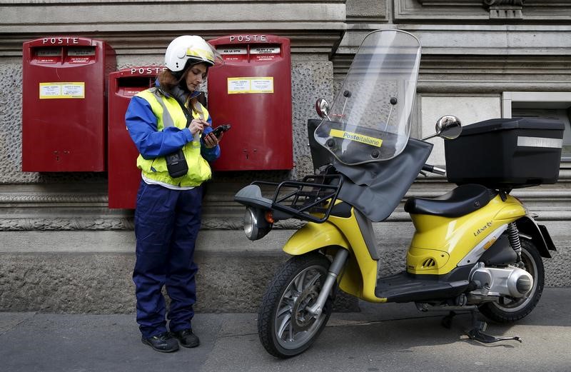 © Reuters. File photo of a postwoman using a device in front of the headquarters of Poste Italiane in Milan