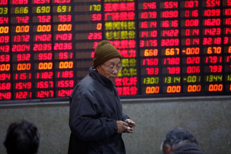 © Reuters. An investor walks in front of an electronic board showing stock information on the first trading day after the New Year holiday at a brokerage house in Shanghai