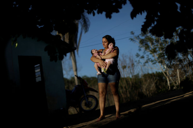 © Reuters. Raquel Barbosa caminha com as filhas gêmeas em Areia, na Paraíba