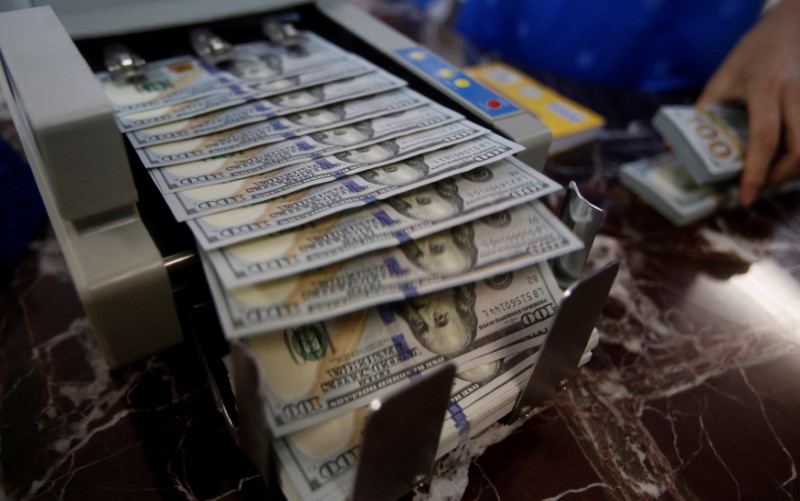 © Reuters. An employee of a bank counts US dollar notes at a branch in Hanoi