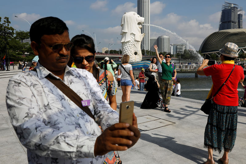 © Reuters. Tourists take photos at the Merlion Park in Singapore