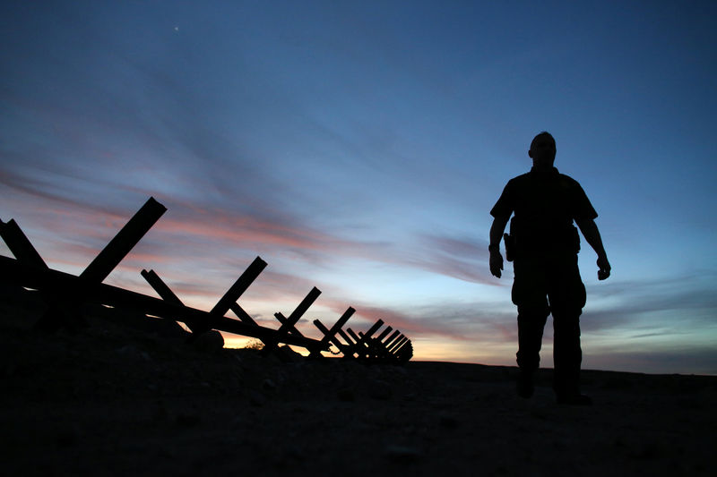 © Reuters. U.S. border patrol agent Alessio Faccin walks along the border fence separating Mexican from the United States near Calexico, California