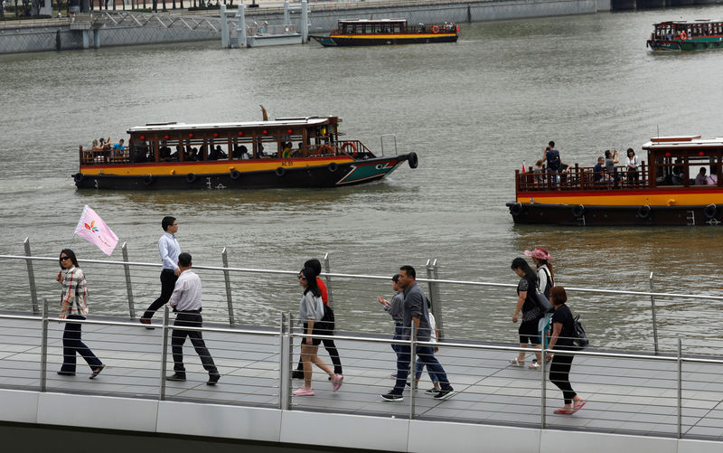 © Reuters. Tourists in bumboats pass a tour group along Marina Bay in Singapore