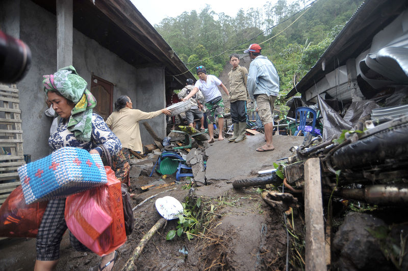 © Reuters. A woman carries her belongings from her damaged house after it was hit by landslide at Songan village in Kintamani