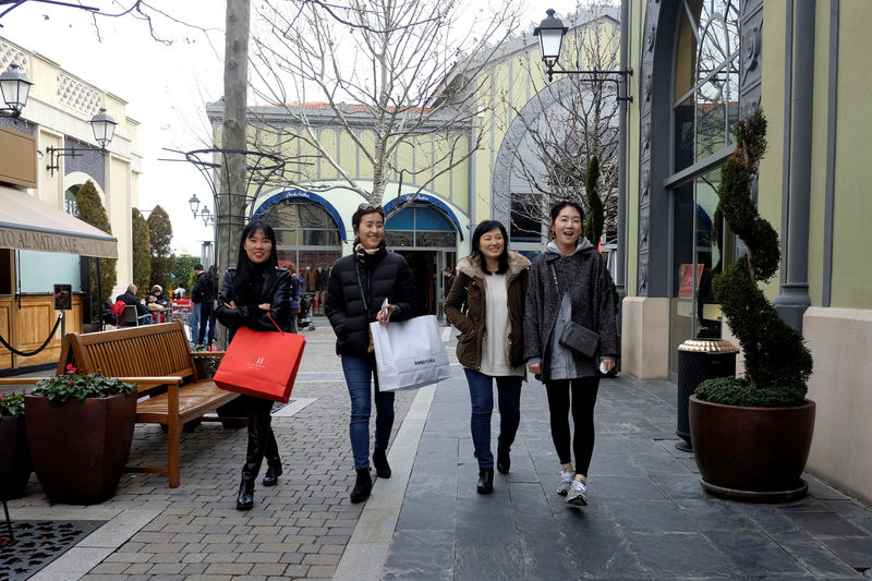 © Reuters. Tourists hold shopping bags as they walk along the Las Rozas Village mall in Las Rozas