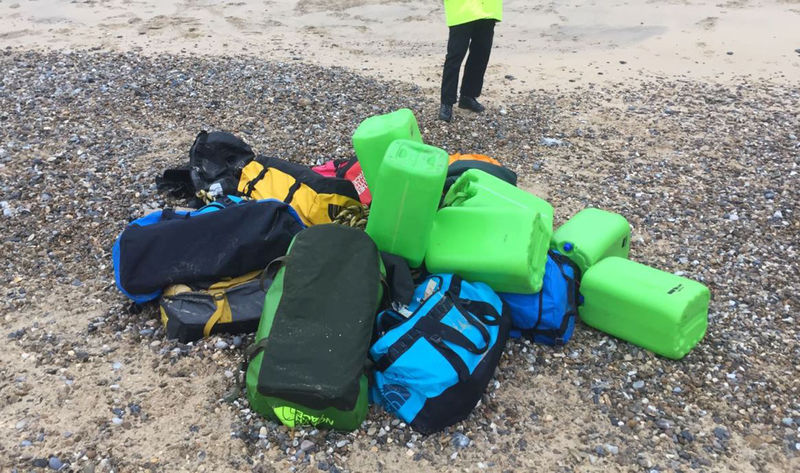 © Reuters. A law enforcement officer stands by holdalls containing cocaine that were washed up on Hopton Beach, near Great Yarmouth, Britain