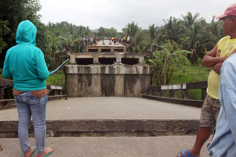 © Reuters. People look at the collapsed Anao-aon bridge after an earthquake hit Surigao city, southern Philippines