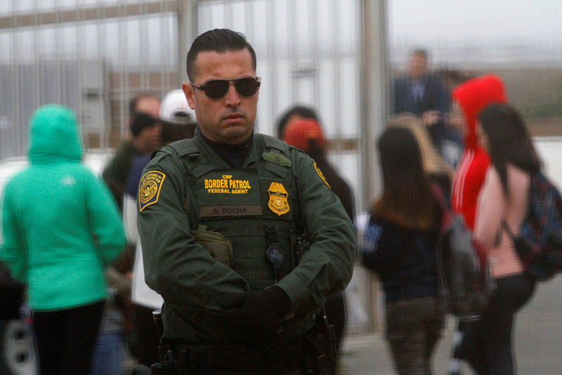 © Reuters. A U.S. Border Patrol agent looks on as people separated by immigration wait to see their relatives at an open gate on the fence along the Mexico and U.S border, as photographed from Tijuana