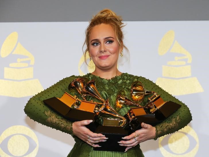 © Reuters. Adele sostiene cinco premios Grammys durante la ceremonia anual en Los Angeles