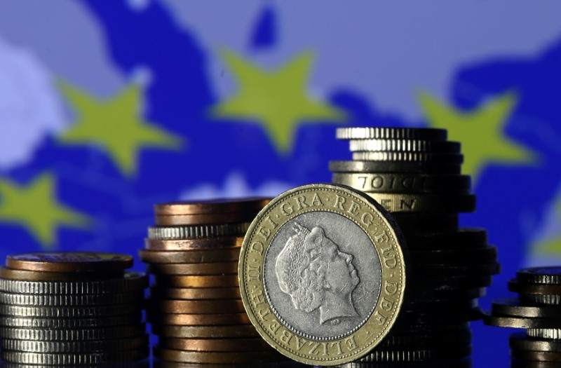 © Reuters. Pound coins are seen in front of a displayed EU flag in this picture illustration