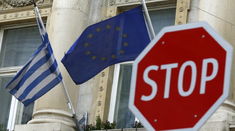 © Reuters. The Greek and EU flags are seen behind a stop sign in front of the Greek embassy in Vienna