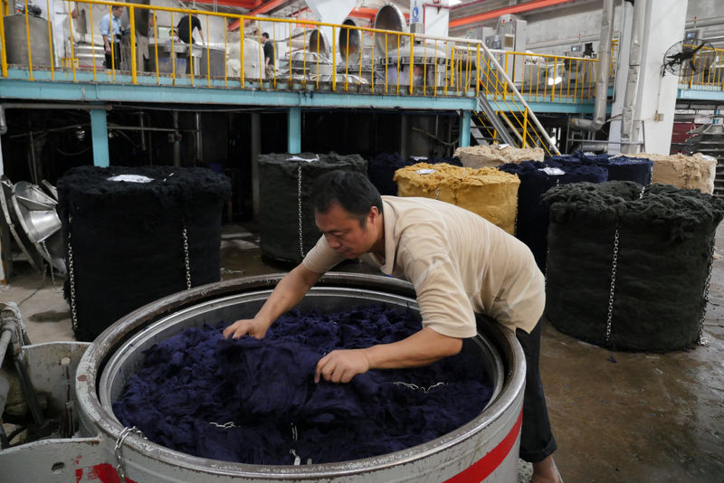 © Reuters. A worker loads wet dyed wool inside a tank to remove excess moisture at a factory owned by Hong Kong's Novetex Textiles Limited in Zhuhai City, Guangdong Province, China