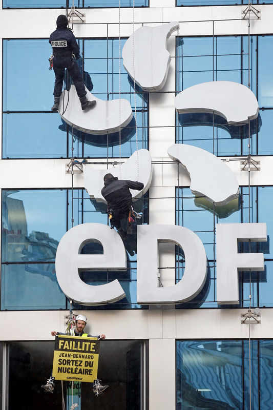 © Reuters. French police intervene as a Greenpeace activist hangs a banner on the facade of the France's state-owned electricity company EDF headquarters in Paris