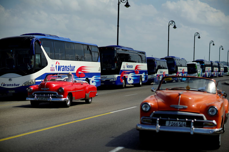 © Reuters. Vintage cars pass by a fleet of Chinese-made Yutong buses parked at the sea front Malecon in Havana, Cuba