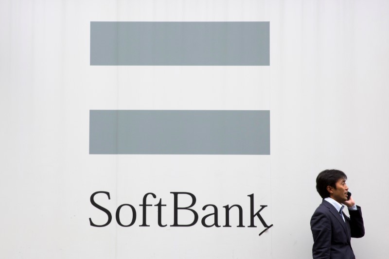 © Reuters. A man talks on the phone as he stand in front of an advertising poster of the SoftBank telecommunications company in Tokyo