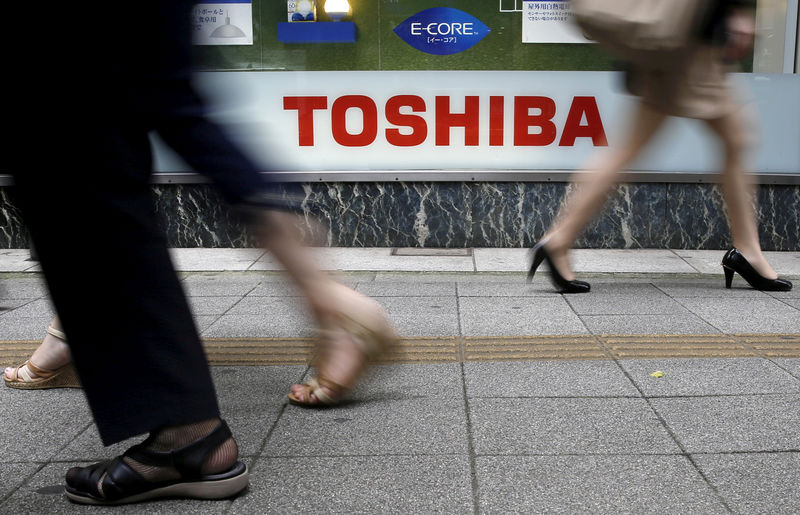 © Reuters. FILE PHOTO -  Pedestrians walk past a logo of Toshiba Corp outside an electronics retailer in Tokyo