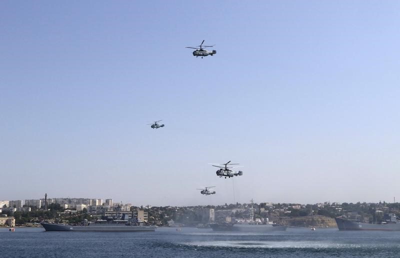 © Reuters. Russian military helicopters fly in formation, with warships seen on the water, during celebrations for Navy Day in the Black Sea port of Sevastopol