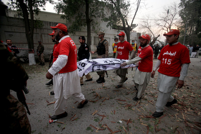 © Reuters. Volunteers move the body of a victim at the scene of a bomb attack in Peshawar