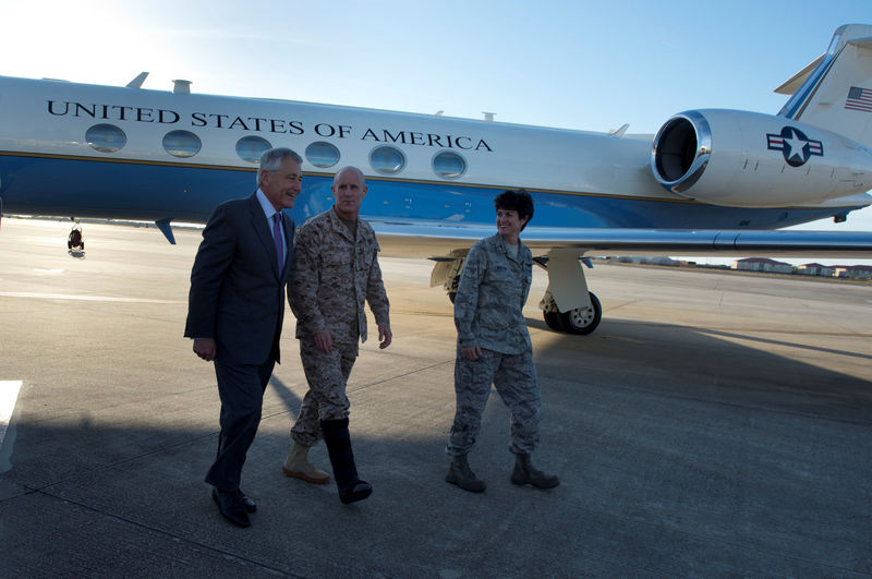 © Reuters. Handout photo of then U.S. Secretary of Defense Hagel walks with Vice Admiral Harward (C) and Colonel Martin, vice commander of 6th Air Mobility Wing, after landing at MacDill Air Force Base, Tampa