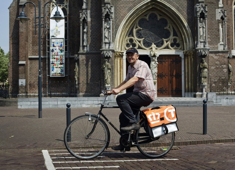 © Reuters. Postnl employee Jaap Bouwmans rides his bicycle to work in his hometown Veghel