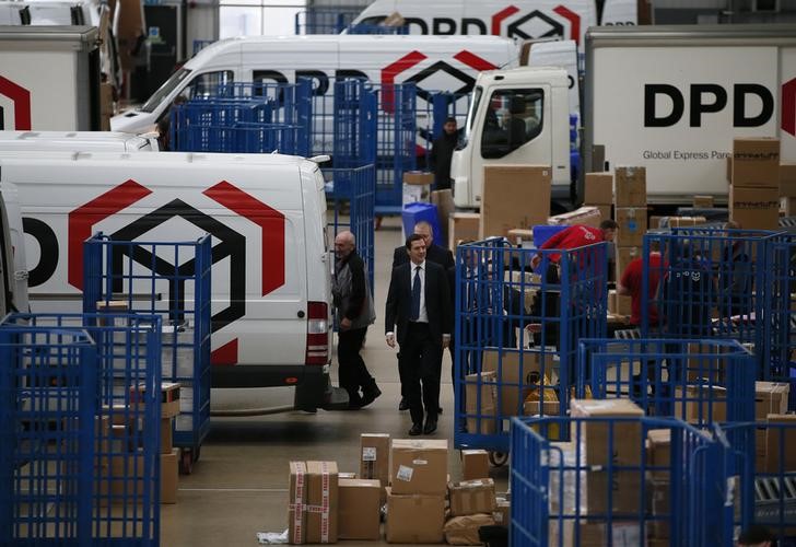 © Reuters. Britain's Chancellor of the Exchequer George Osborne walks past delivery vans during a visit to the DPD parcels depot in Raunds