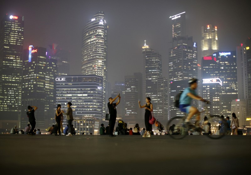 © Reuters. People take photos with the skyline of the central business district in Singapore