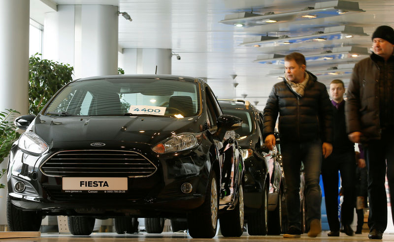 © Reuters. FILE PHOTO:  Visitors walk past Ford cars at a dealership in Moscow