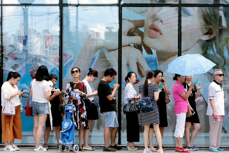 © Reuters. FILE PHOTO:  People queue outside of a newly opened duty free shop in Shanghai
