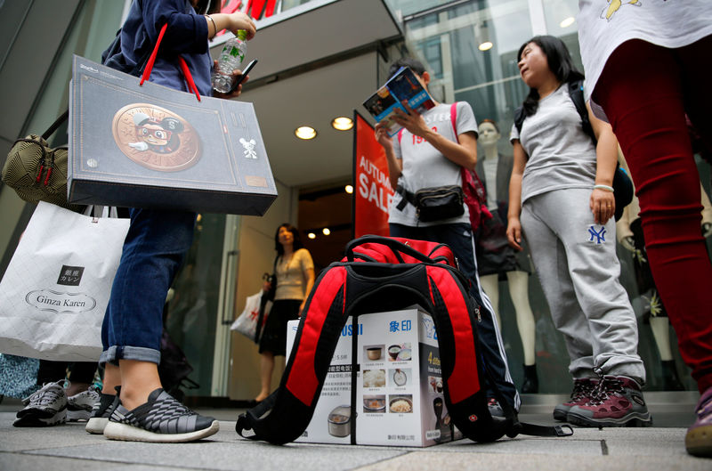 © Reuters. FILE PHOTO:  Chinese tourists wait for their bus on a street in Tokyo's Ginza shopping district
