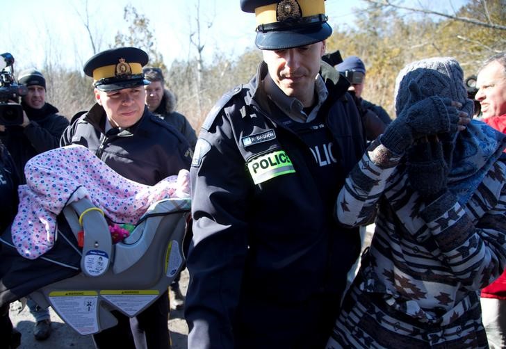 © Reuters. Mãe e bebê são levados pela polícia na fronteira entre EUA e Canadá