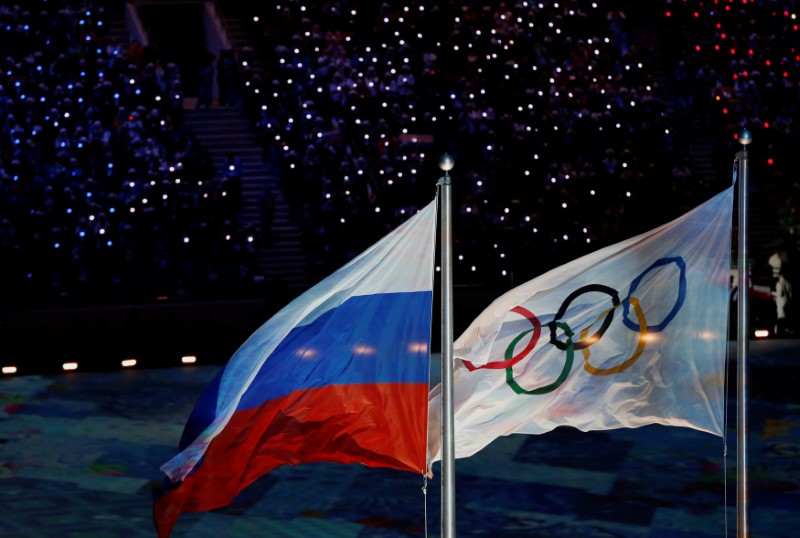 © Reuters. Russian national flag flutters next to Olympics flag during closing ceremony for 2014 Sochi Winter Olympics