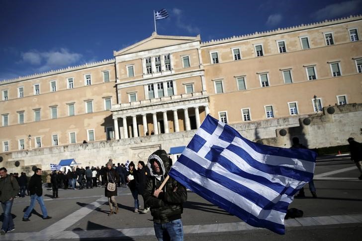 © Reuters. A farmer waves a Greek national flag in front of the parliament building during a demonstration to demand tax reductions and compensation, in Athens
