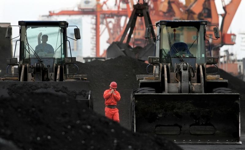 © Reuters. File Photo: An employee walks between front-end loaders which are used to move coal imported from North Korea at Dandong port in the Chinese border city of Dandong