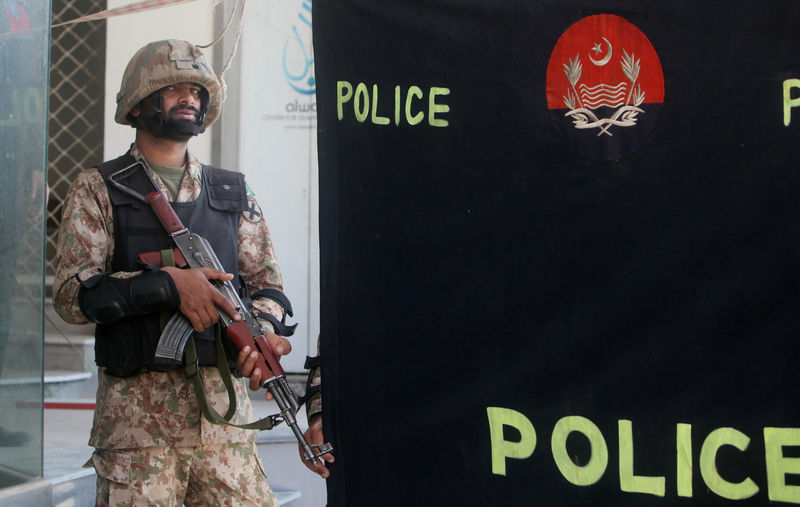 © Reuters. A soldier stands guard at the police screen as investigators collect evidence at the scene of a blast in a upscale neighborhood in Lahore