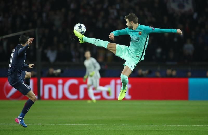 © Reuters. Barcelona's Gerard Pique in action with Paris Saint-Germain's Angel Di Maria