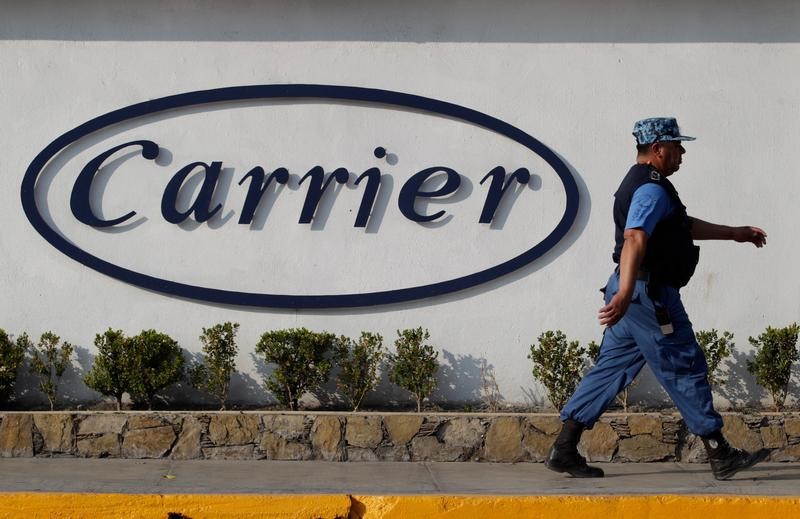 © Reuters. Private security guard walks past a logo of Carrier Corp outside the air conditioner plant, a unit of United Technologies Corp, in Santa Catarina