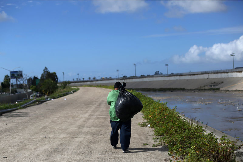 © Reuters. A Mexican who was recently deported from the U.S. carries a black bag next Tijuana river