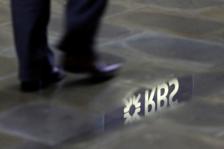 © Reuters. A man walks past a  Royal Bank of Scotland branch reflected in a puddle in central London