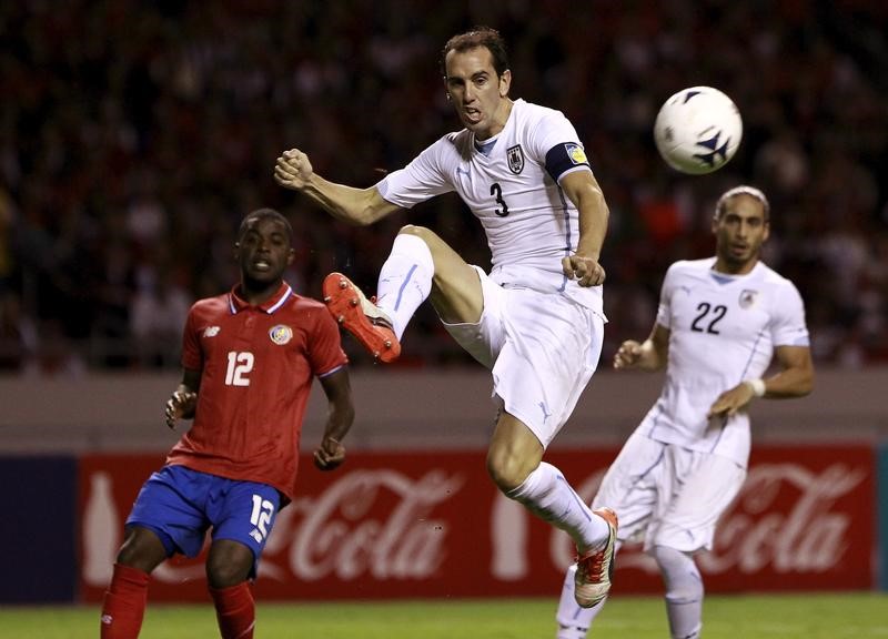 © Reuters. Uruguay's Godin kicks the ball near his team mates Caceres and Costa Rica's Campbell during their international soccer friendly match at the National stadium in San Jose