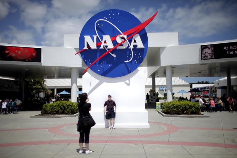 © Reuters. Tourists take pictures of a NASA sign at the Kennedy Space Center visitors complex in Cape Canaveral, Florida