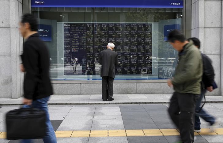 © Reuters. Man looks at a stock quotation board outside a brokerage in Tokyo