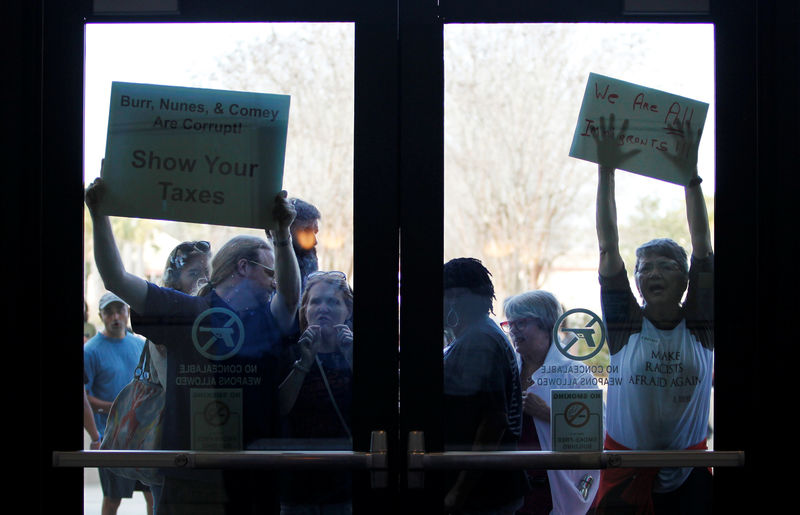 © Reuters. People who could not get into the event because of space limits, hold signs for their cause outside a town hall meeting for constituents hosted by U.S. Senator Tim Scott in North Charleston