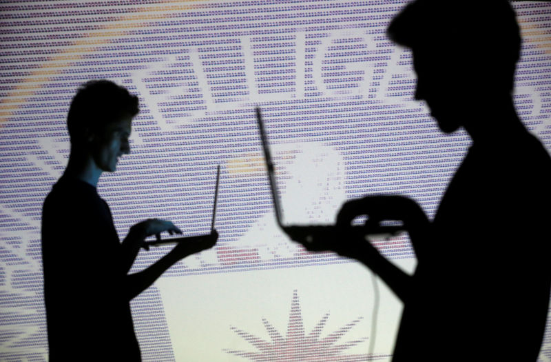 © Reuters. FILE PHOTO: People pose with laptops in front of projection of  binary code and CIA emblem in this picture illustration taken in Zenica