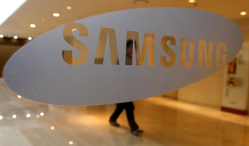 © Reuters. FILE PHOTO - A man walks behind a logo of Samsung Electronics at the company's headquarters in Seoul